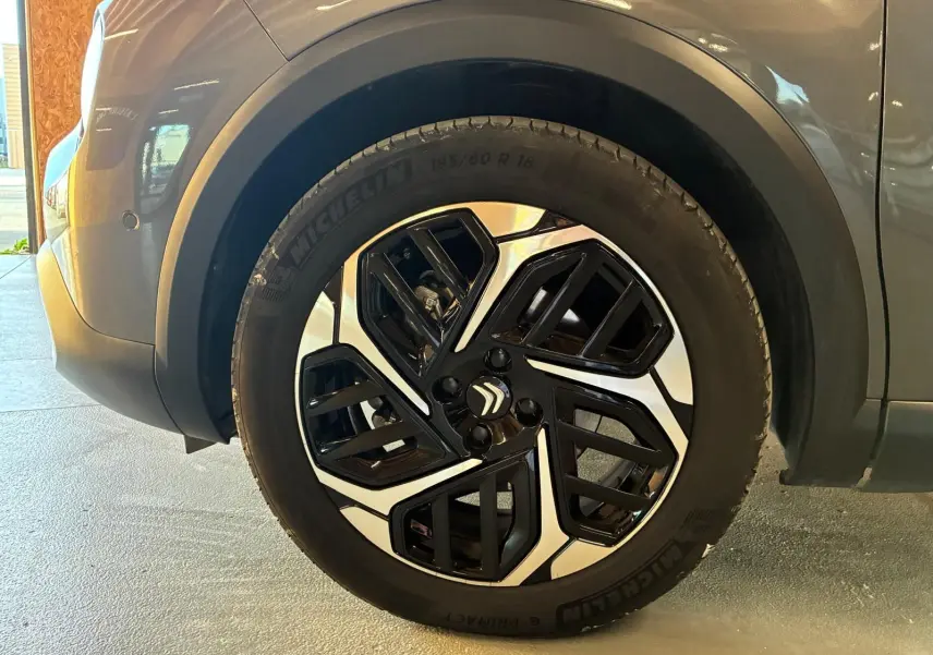 Gros plan sur la roue avant gauche d'une Citroën C4 X gris 2024, jante alliage bicolore au design moderne.