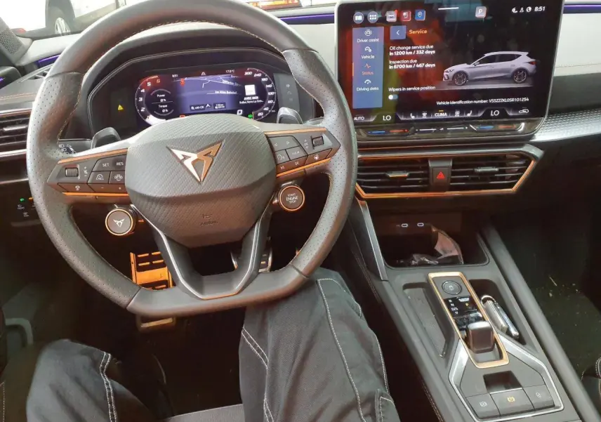 Vue intérieure centrée sur le volant cuir perforé et l'écran tactile du tableau de bord de la CUPRA Leon 2025.