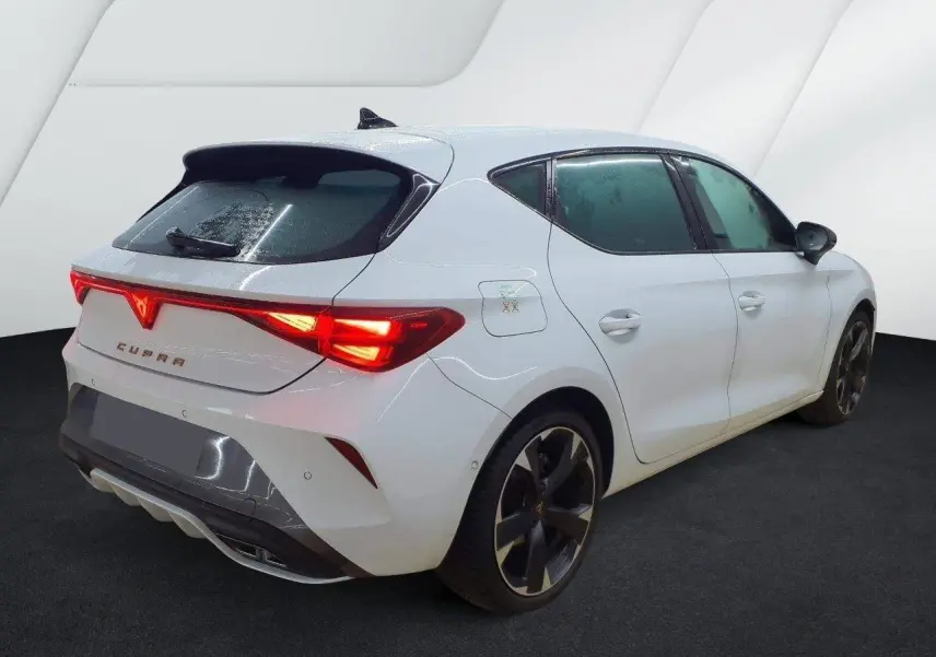 Vue 3/4 arrière droite d'une CUPRA Leon blanc Nevada avec feux arrière LED et jantes alliage 18 pouces.