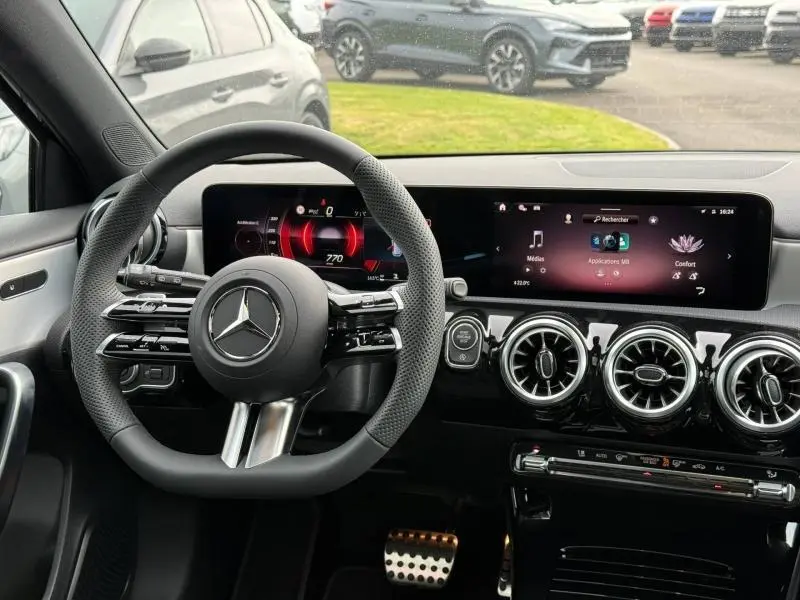 Vue intérieure du poste de conduite de la Mercedes Classe A 200 d AMG Line 2026 avec volant sport et écran tactile large.
