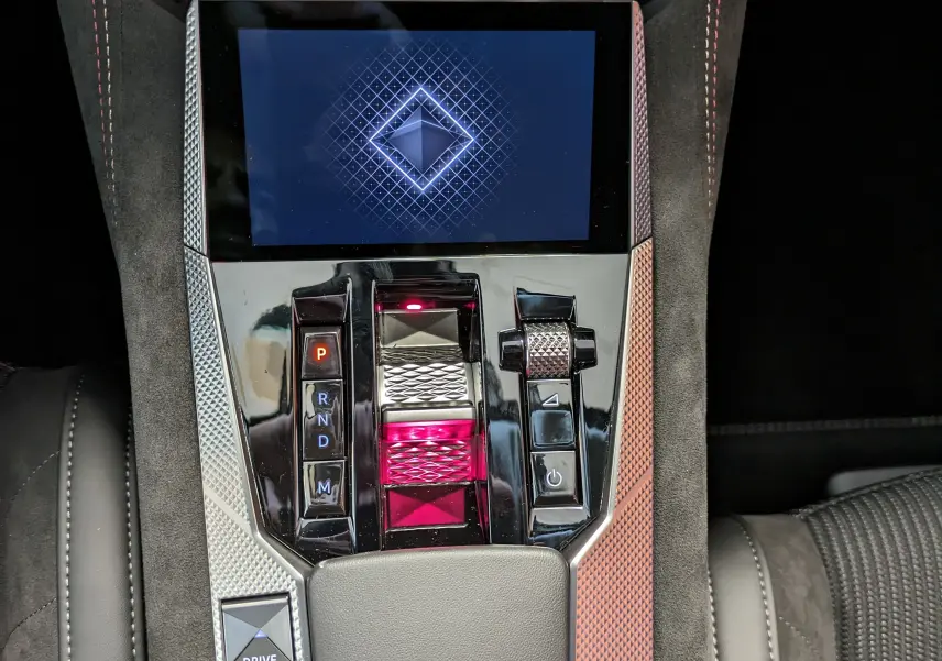 Vue plongeante sur la console centrale noire et argentée du DS4 blanc nacré, avec écran tactile et commandes de boîte auto.