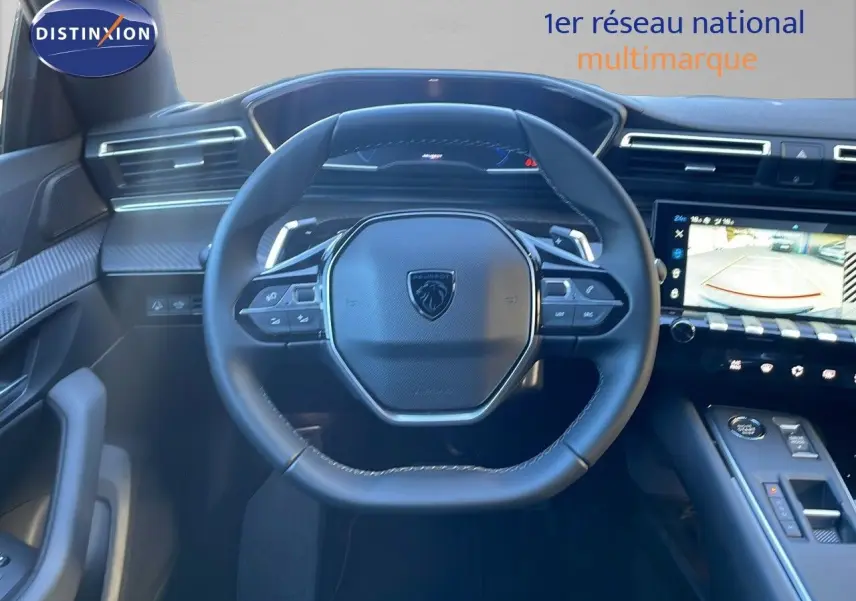Vue intérieure centrée sur le volant cuir noir du Peugeot 508 SW 2024 avec écran tactile et caméra de recul affichée.