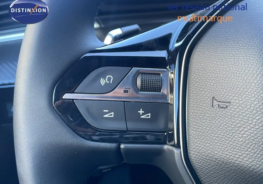 Gros plan sur les commandes gauche du volant en cuir noir de la Peugeot 508 SW 2024 finition Allure.