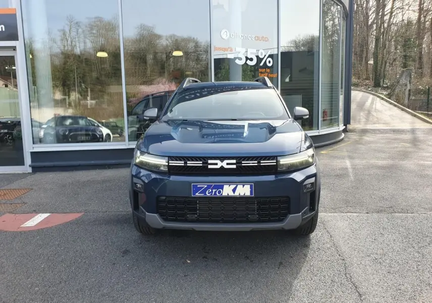 Vue frontale d’un Dacia Bigster bleu indigo avec signature lumineuse LED et toit panoramique visible.