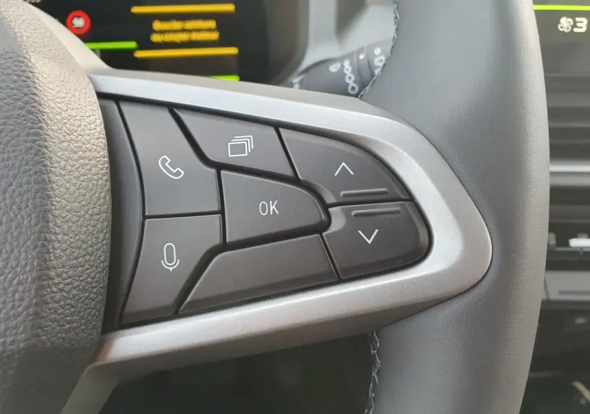 Gros plan sur les commandes multifonctions à droite du volant du Dacia Bigster, boutons noirs et contour argenté.