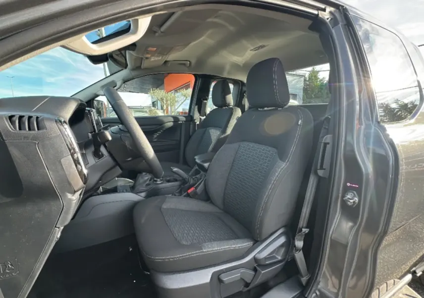 Vue intérieure côté conducteur du Ford Ranger gris carbone 2025, mettant en valeur les sièges avant et le volant multifonctions cuir.