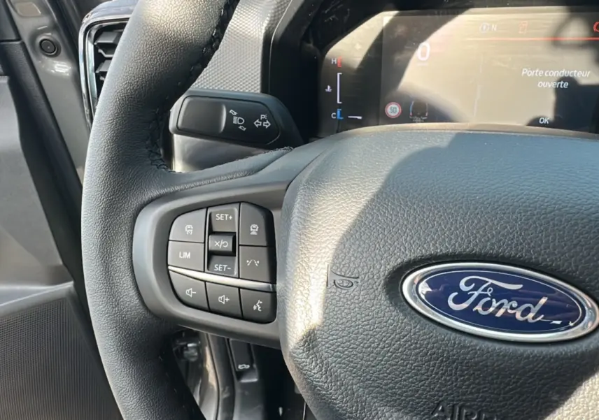 Gros plan sur le volant cuir multifonctions du Ford Ranger gris carbone, avec tableau de bord numérique en arrière-plan.