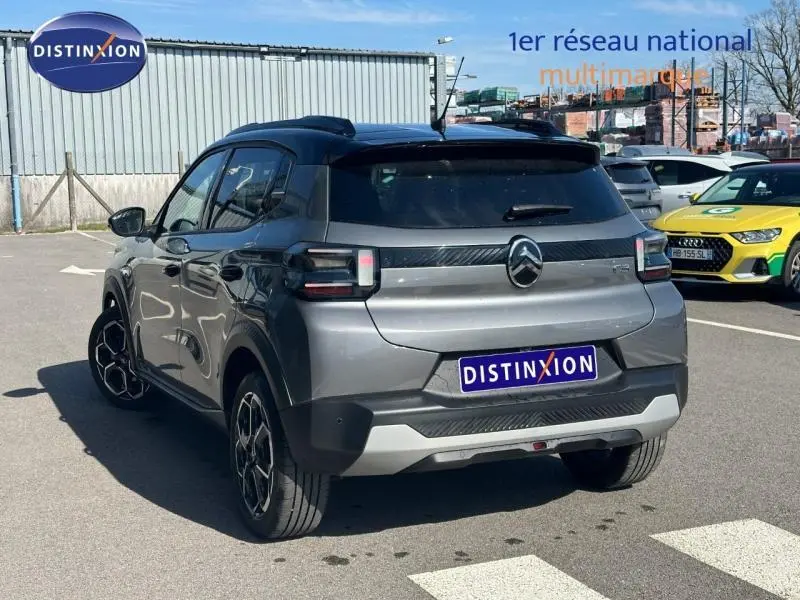 Vue 3/4 arrière droite d'une Citroën C3 2025 noire avec détails noirs mats et jantes distinctives sur parking extérieur.