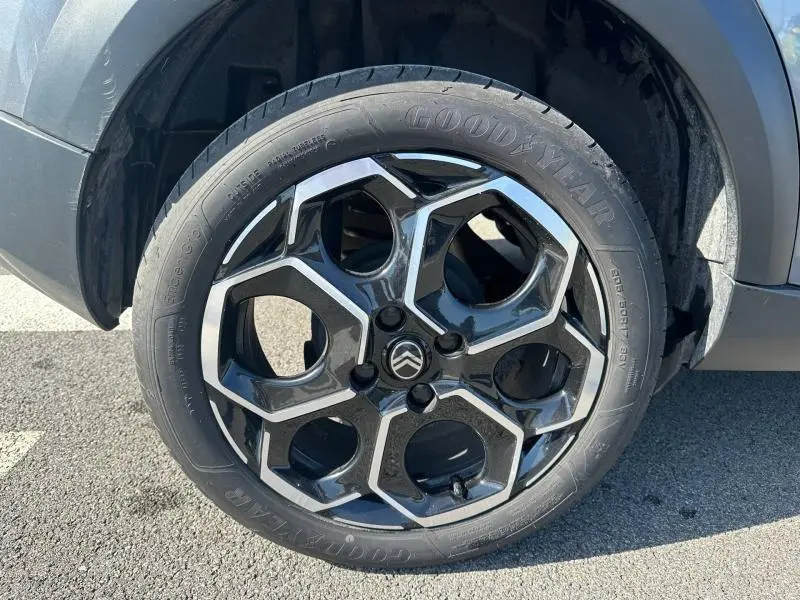 Gros plan sur la roue avant droite d'une Citroën C3 noire 2025, mettant en valeur la jante alliage au design hexagonal.