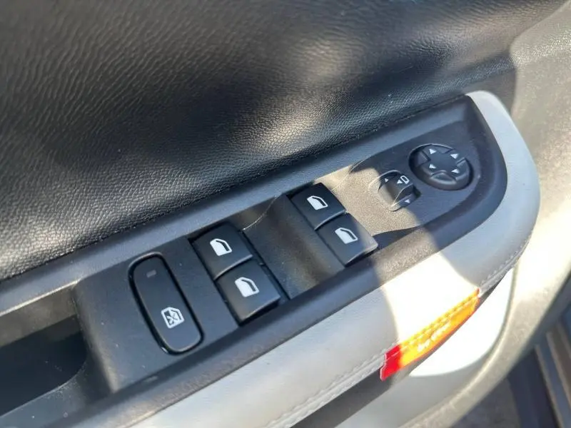 Détail des commandes des vitres et rétroviseurs sur la porte intérieure côté conducteur de la Citroën C3 noire 2025.