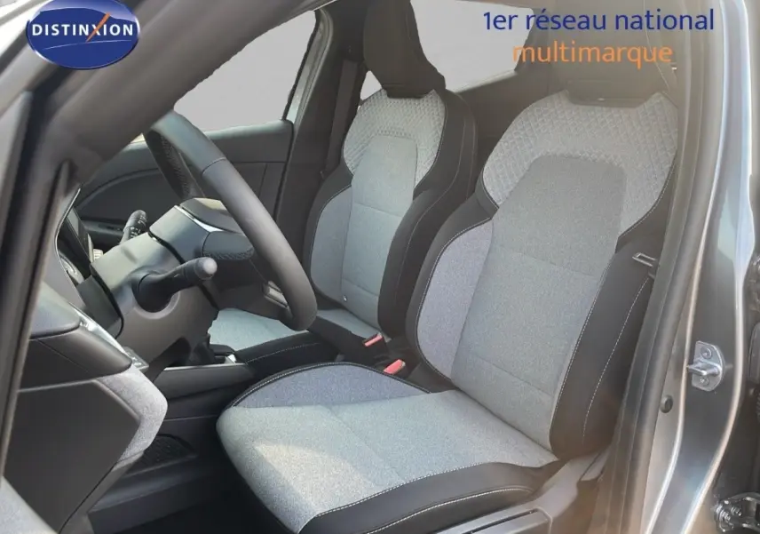 Vue intérieure côté conducteur de la Renault Clio 2025 avec sièges tissu gris clair et noir, volant multifonctions cuir synthétique.