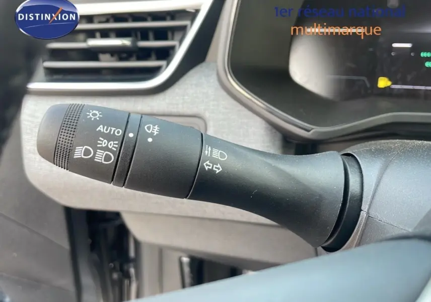 Gros plan sur la commande des phares et clignotants à gauche du volant dans l’habitacle gris d’une Renault Clio 2025.