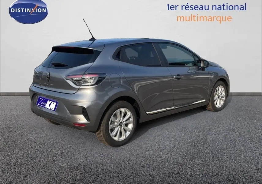 Vue 3/4 arrière droite d'une Renault Clio gris métallisé garée devant un mur blanc avec logo Distinxion.