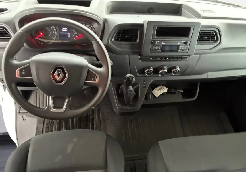 Vue intérieure du tableau de bord et volant du Renault Master blanc 2024, avec boîte manuelle et commandes centrales visibles.