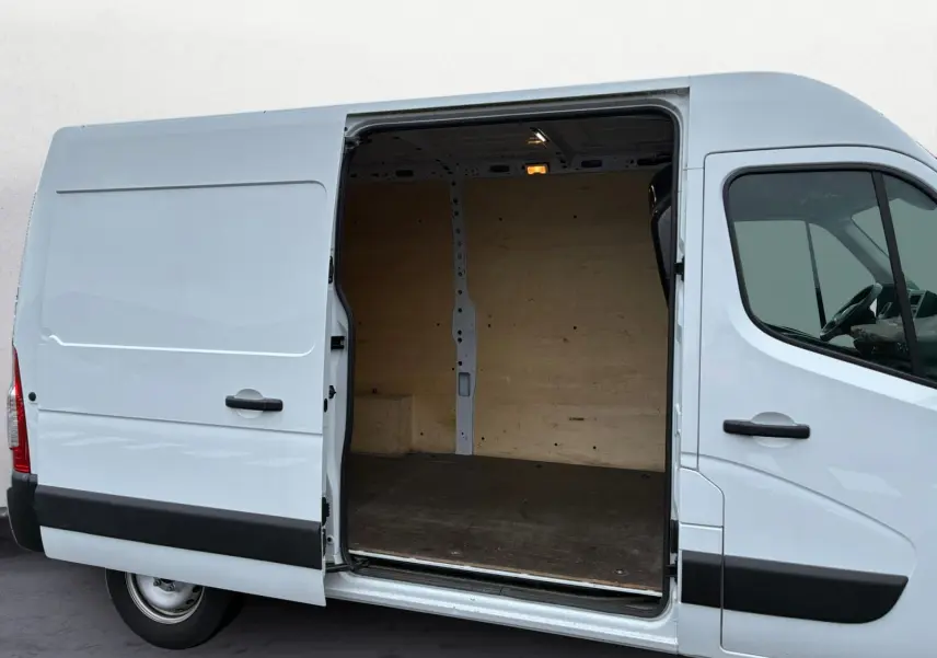 Vue latérale droite d’un Renault Master blanc 2024 avec porte coulissante ouverte montrant l’intérieur en bois du coffre.