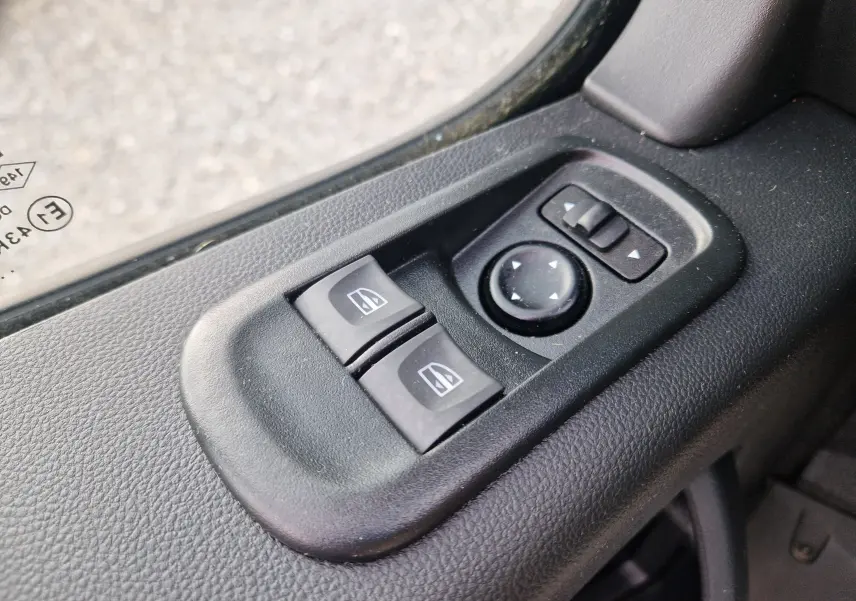 Gros plan sur les commandes électriques des vitres et réglage des rétroviseurs côté conducteur du Renault Master blanc 2024.