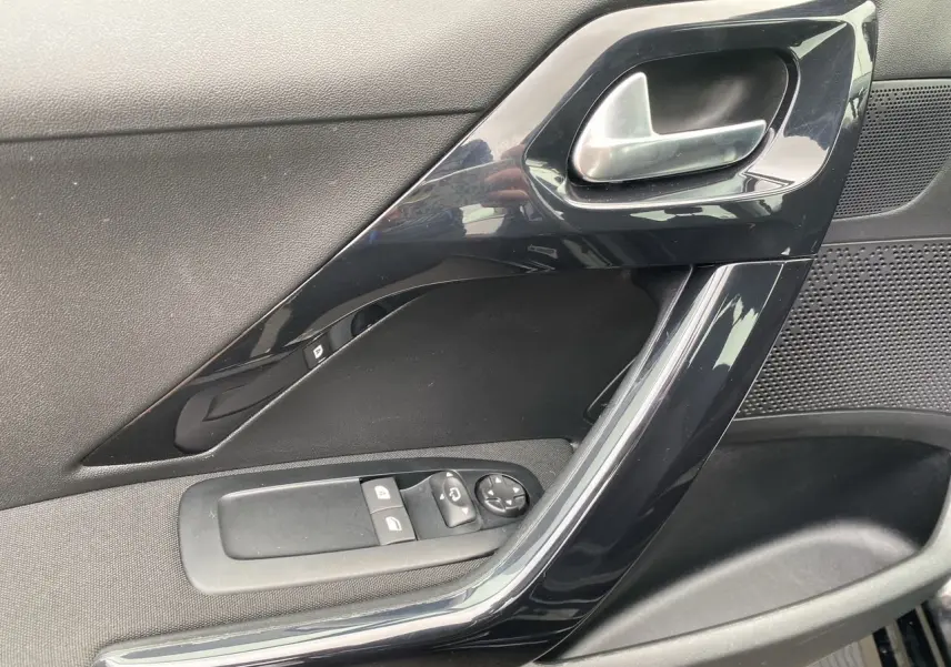 Détail de la porte côté gauche noire de la Peugeot 208 AFFAIRE avec commandes électriques et poignée argentée.