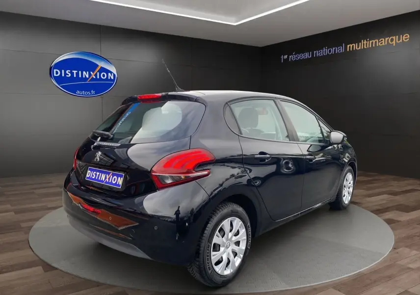 Peugeot 208 Affaire noir vue 3/4 arrière droit en intérieur, avec feux arrière rouges et jantes argentées.