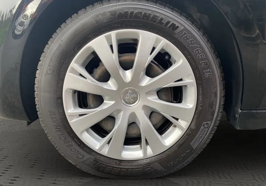 Gros plan sur la roue avant gauche d'une Peugeot 208 Affaire noire, avec jante en alliage et pneu Michelin visible.