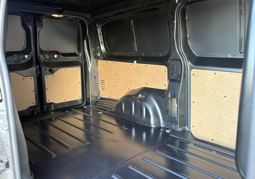 Intérieur du coffre du Citroën Jumpy XL gris titane, vue côté gauche avec panneaux de protection en bois clair.