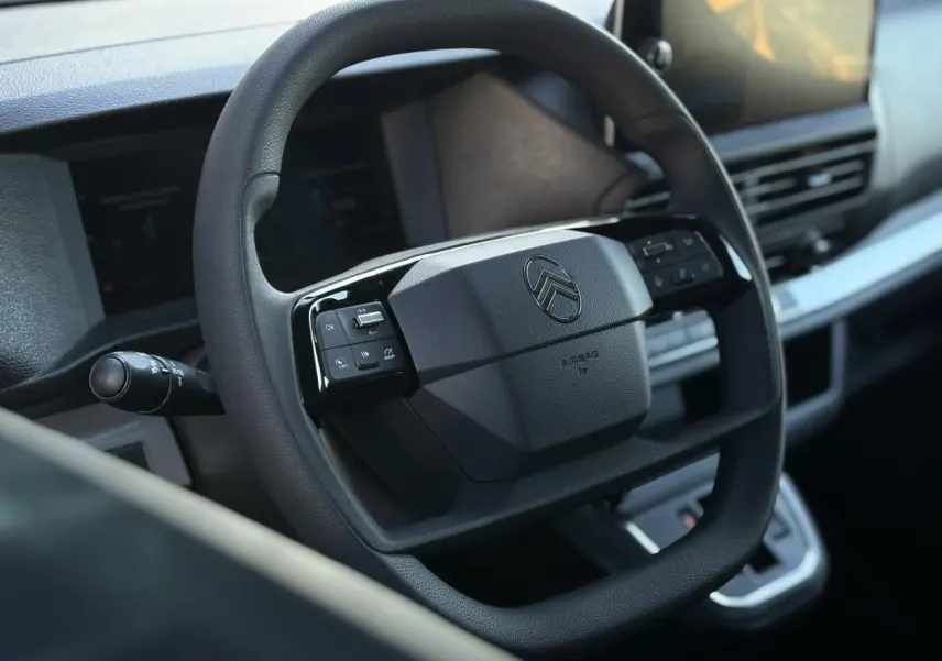 Volant noir avec commandes intégrées et logo Citroën, vue rapprochée de l'habitacle moderne du Jumpy XL gris Titane.