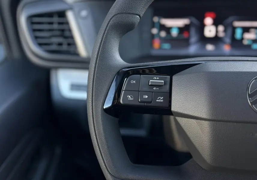 Gros plan sur les commandes au volant à gauche du Citroën Jumpy XL gris Titane, tableau de bord flou en arrière-plan.