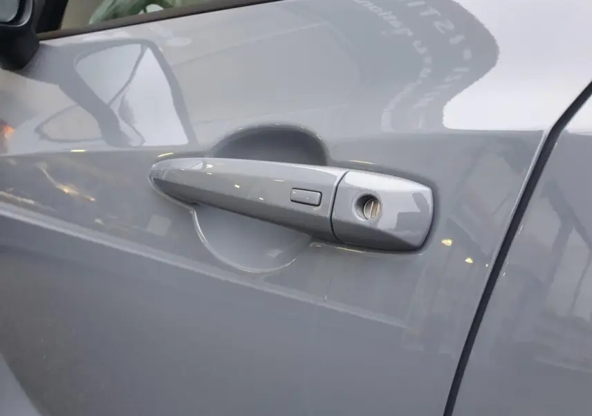 Poignée de porte côté gauche gris céramique du Nissan Juke 2025 avec bouton de verrouillage intégré.