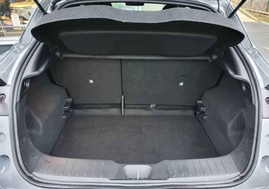 Coffre ouvert vu de l'arrière d'un Nissan Juke gris céramique, montrant l'espace de chargement et la banquette rabattable.