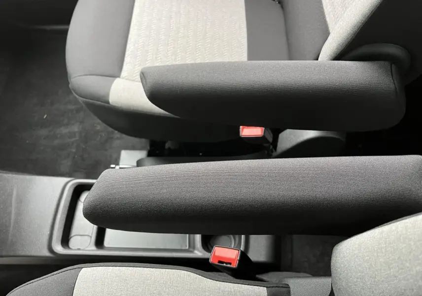 Vue rapprochée des accoudoirs noirs et sièges bicolores gris clair et foncé du Citroën Berlingo Multispace blanc Glacier.