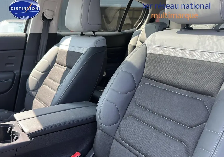 Intérieur du Citroën C5 Aircross 2024, vue sur sièges avant en tissu brun et cuir noir avec accoudoir central.