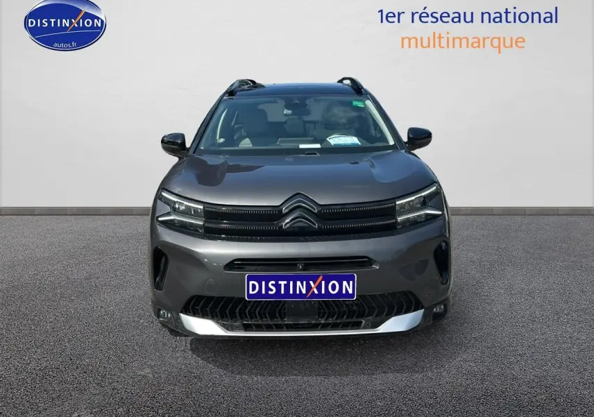 Vue avant d'un Citroën C5 Aircross gris platinium avec calandre distinctive et barres de toit visibles.