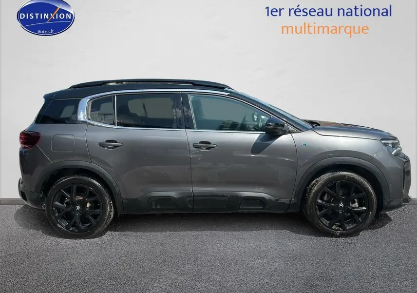 Profil côté gauche du Citroën C5 Aircross hybride rechargeable 2024 gris platinium avec jantes noires et barres de toit.