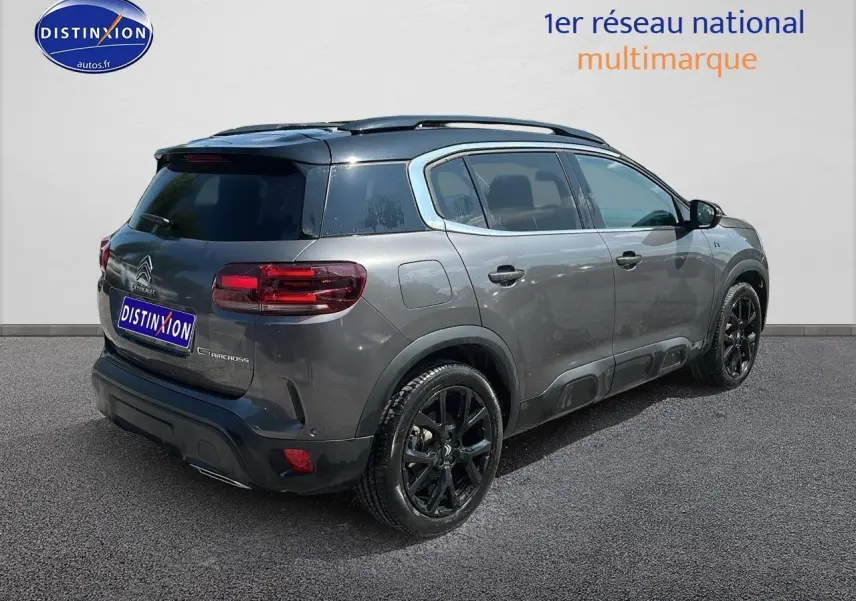 Vue 3/4 arrière droite d'un Citroën C5 Aircross gris platinium avec jantes noires et toit noir.