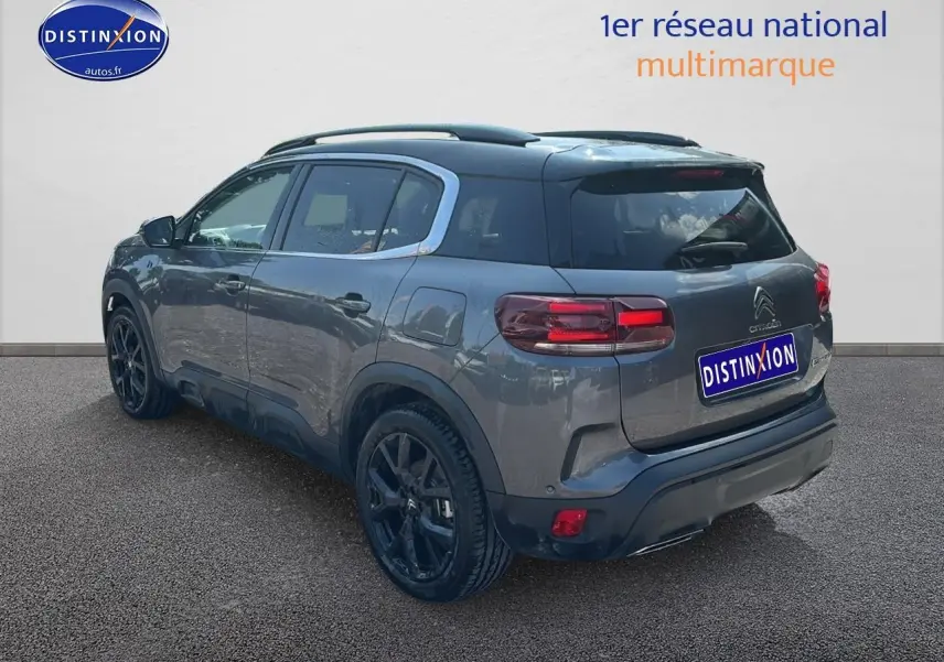 Vue 3/4 arrière droite du Citroën C5 Aircross gris platinium avec barres de toit et jantes noires.