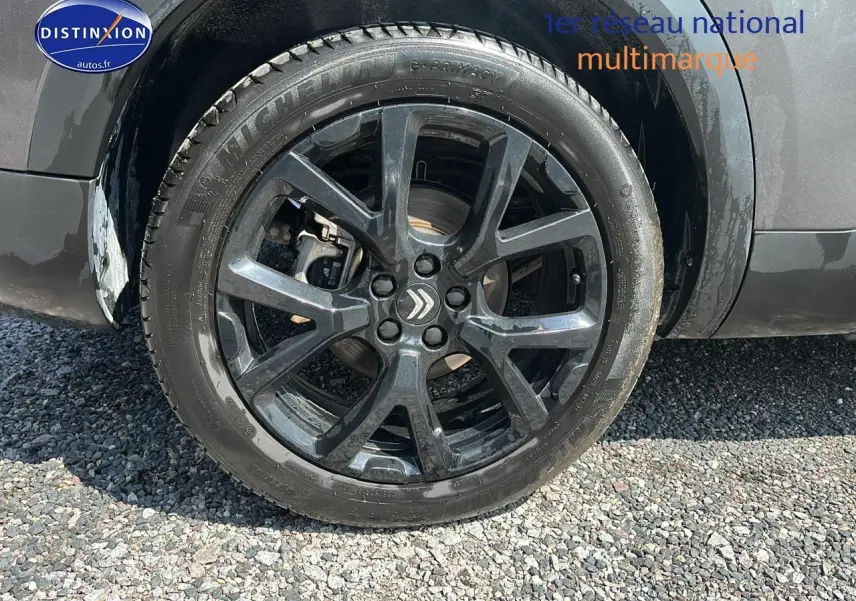 Gros plan sur la roue avant gauche avec jante alliage noire du Citroën C5 Aircross gris platinium 2024 hybride rechargeable.