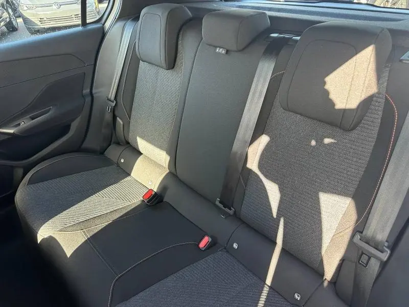 Vue intérieure de la banquette arrière en tissu gris avec appuie-têtes et ceintures de sécurité visibles.