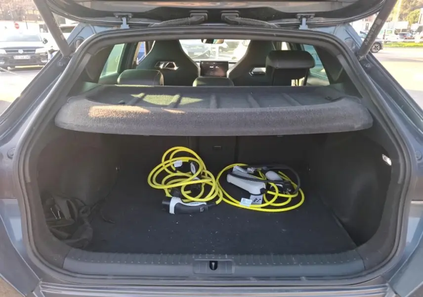 Coffre ouvert vu de l'arrière d'une CUPRA Formentor gris foncé 2023 avec câbles de recharge hybride visibles à l'intérieur.