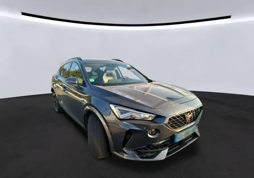 Vue 3/4 avant du CUPRA Formentor gris foncé 2023 avec calandre distinctive et jantes noires, posé sur fond neutre.