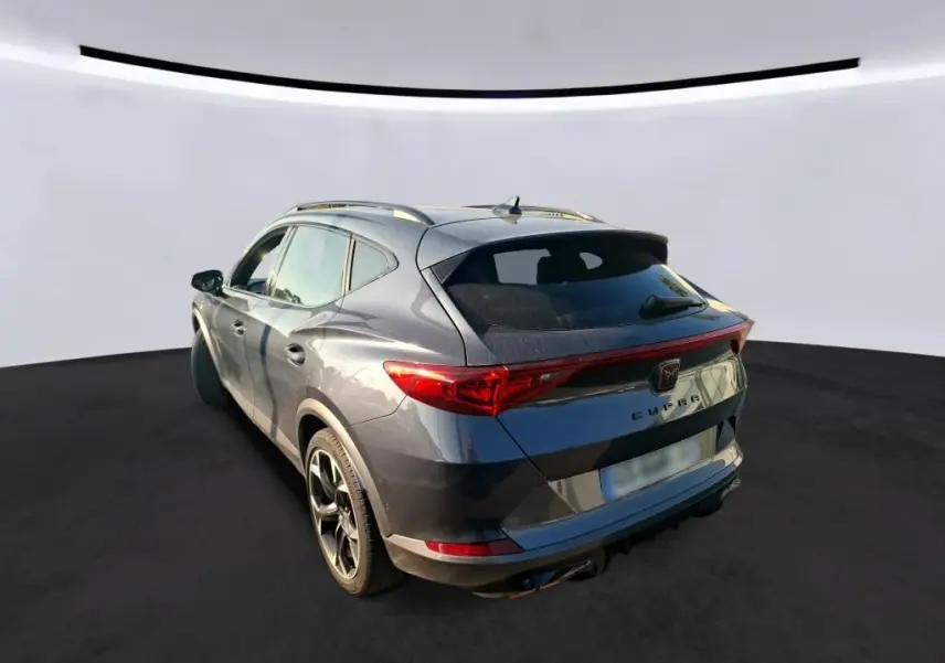 Vue 3/4 arrière droite d'une CUPRA Formentor gris foncé 2023 avec feux arrière reliés et toit ouvrant.