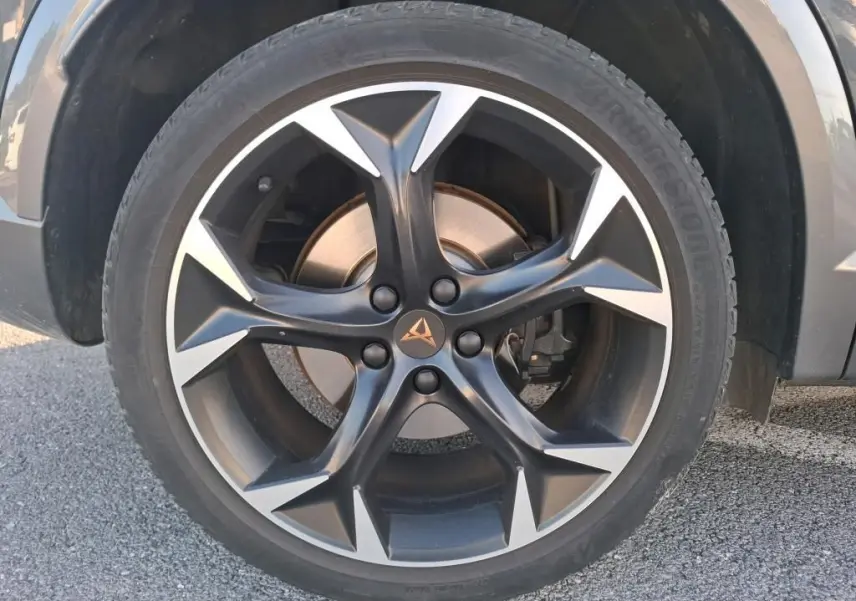 Gros plan sur la roue avant droite d'une CUPRA Formentor gris foncé, jante alliage noire et argentée au design sportif.