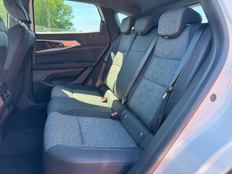 Vue latérale droite de l'intérieur arrière du Renault Austral 2025, sièges tissu gris clair avec appuie-têtes intégrés.