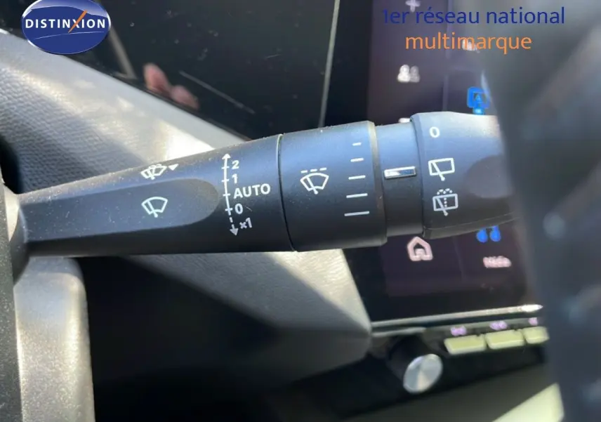 Gros plan sur la commande des essuie-glaces dans l’habitacle du Peugeot 308 SW gris Artense, avec écran tactile en arrière-plan.