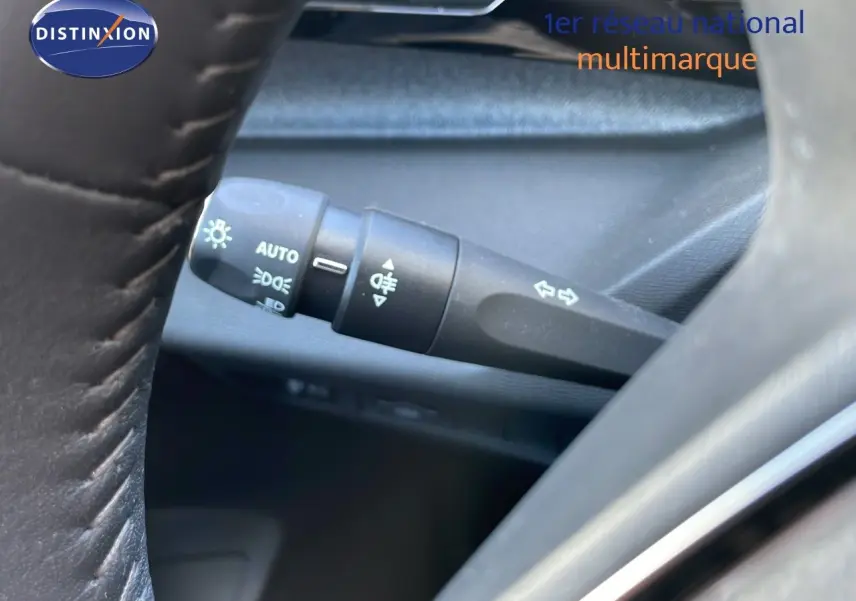 Gros plan sur la manette de clignotant et feux, à gauche du volant en cuir noir du Peugeot 308 SW gris Artense.
