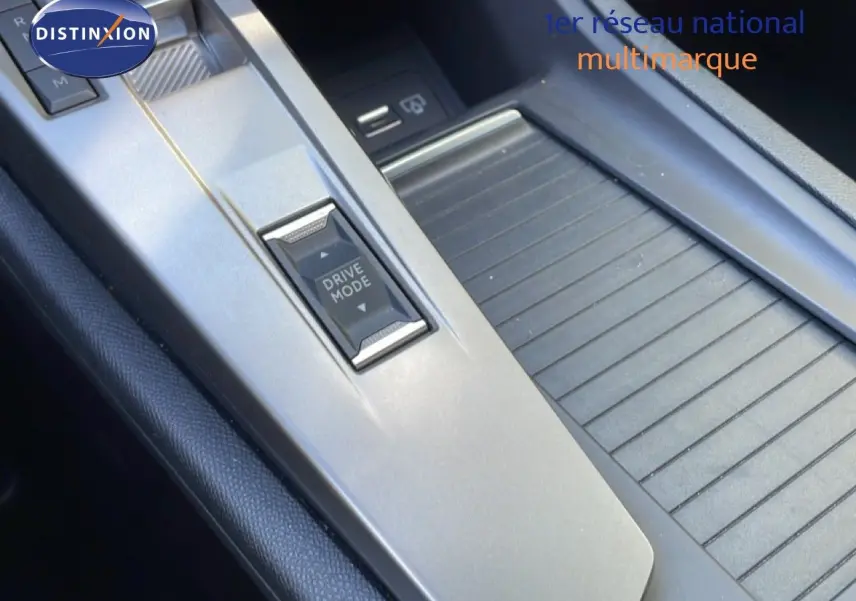 Détail de la console centrale grise de la Peugeot 308 SW Hybrid 2025 avec bouton Drive Mode et rangement coulissant.