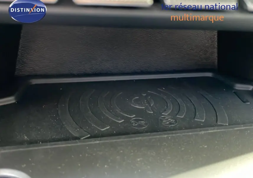 Gros plan sur le chargeur sans fil intérieur du Peugeot 308 SW gris Artense Metal, mettant en valeur la surface antidérapante.