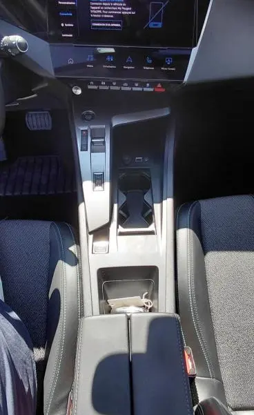 Vue intérieure centrée sur la console centrale et l'écran tactile du Peugeot 308 Hybrid gris avec accoudoir central.
