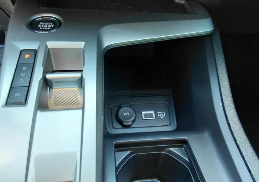 Vue rapprochée de la console centrale grise du Peugeot 308 Hybrid 145 e-DCS6 Allure avec bouton start, levier de vitesses et ports USB et 12V.