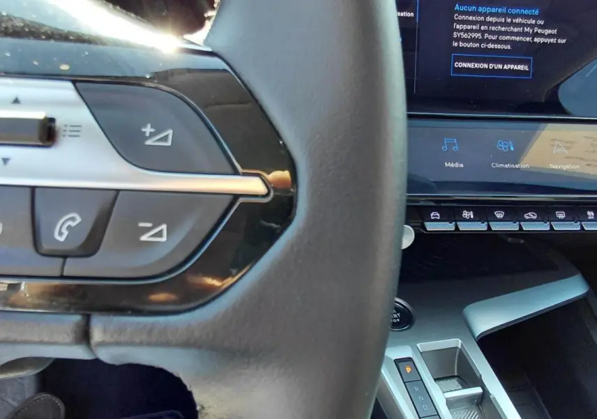 Gros plan sur le volant et la console centrale de la Peugeot 308 Hybrid 145 gris, montrant les commandes au volant et l’écran tactile.