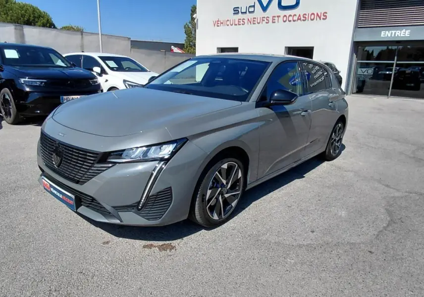 Peugeot 308 Hybrid gris vue 3/4 avant droit, avec jantes alliage 17 pouces et calandre noire distinctive.