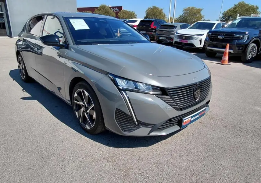 Peugeot 308 Hybrid gris vue 3/4 avant droit, avec jantes alliage et calandre au lion noir mat.